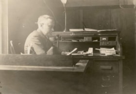 Hans Olson sitting at a desk at Hanson Lumber and Timber Co. office. (Images are provided for educational and research purposes only. Other use requires permission, please contact the Museum.) thumbnail