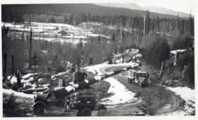 Log balanced on two trucks across a logging road. (Images are provided for educational and research purposes only. Other use requires permission, please contact the Museum.) thumbnail