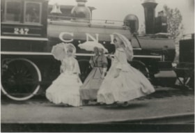 3 women in front of a Canadian National Railways engine wearing hoopskirts and carrying parasols. (Images are provided for educational and research purposes only. Other use requires permission, please contact the Museum.) thumbnail