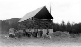 Men using bailing machine in front of hay barn.. (Images are provided for educational and research purposes only. Other use requires permission, please contact the Museum.) thumbnail