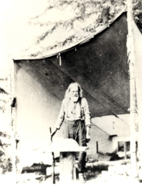 Elderly man standing in the mouth of a canvas shelter. (Images are provided for educational and research purposes only. Other use requires permission, please contact the Museum.) thumbnail