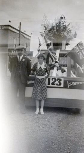 Couple in front of a float, Main Street. (Images are provided for educational and research purposes only. Other use requires permission, please contact the Museum.) thumbnail