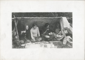 Four women eating under a lean-to. (Images are provided for educational and research purposes only. Other use requires permission, please contact the Museum.) thumbnail