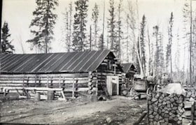 Freight wagon in front of a log storage building.. (Images are provided for educational and research purposes only. Other use requires permission, please contact the Museum.) thumbnail