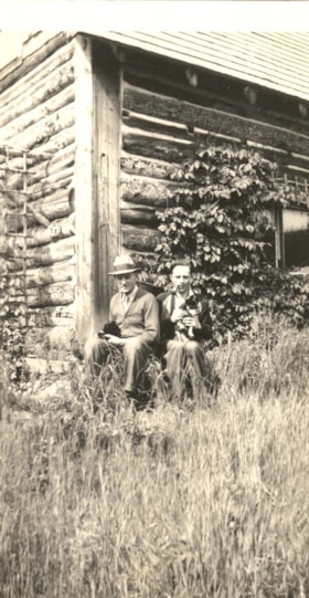 Unidentified men holding puppies in front of a cabin. (Images are provided for educational and research purposes only. Other use requires permission, please contact the Museum.) thumbnail