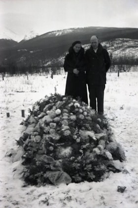 Man and woman standing at grave. (Images are provided for educational and research purposes only. Other use requires permission, please contact the Museum.) thumbnail