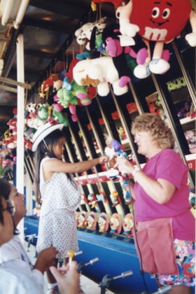 Girl receiving prize at midway game. (Images are provided for educational and research purposes only. Other use requires permission, please contact the Museum.) thumbnail