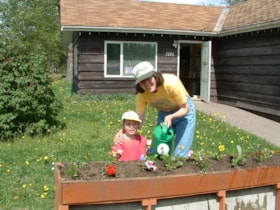 Woman and child watering flowers, Telkwa Community Planting Day. (Images are provided for educational and research purposes only. Other use requires permission, please contact the Museum.) thumbnail