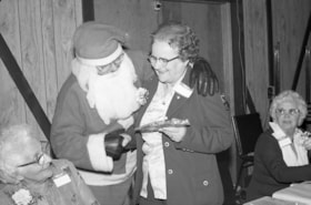 Santa Claus giving a gift at senior citizens' Christmas dinner, Houston. (Images are provided for educational and research purposes only. Other use requires permission, please contact the Museum.) thumbnail